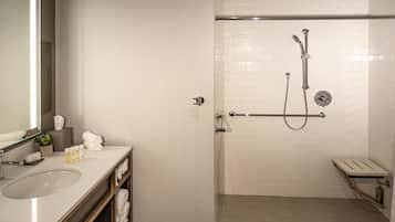 Un baño moderno con lavamanos blanco, espejo y cabina de ducha con puerta de vidrio.