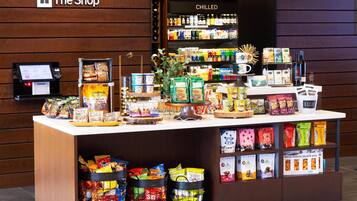 A snack display in a store with various packaged snacks and a refrigerated section in the background.