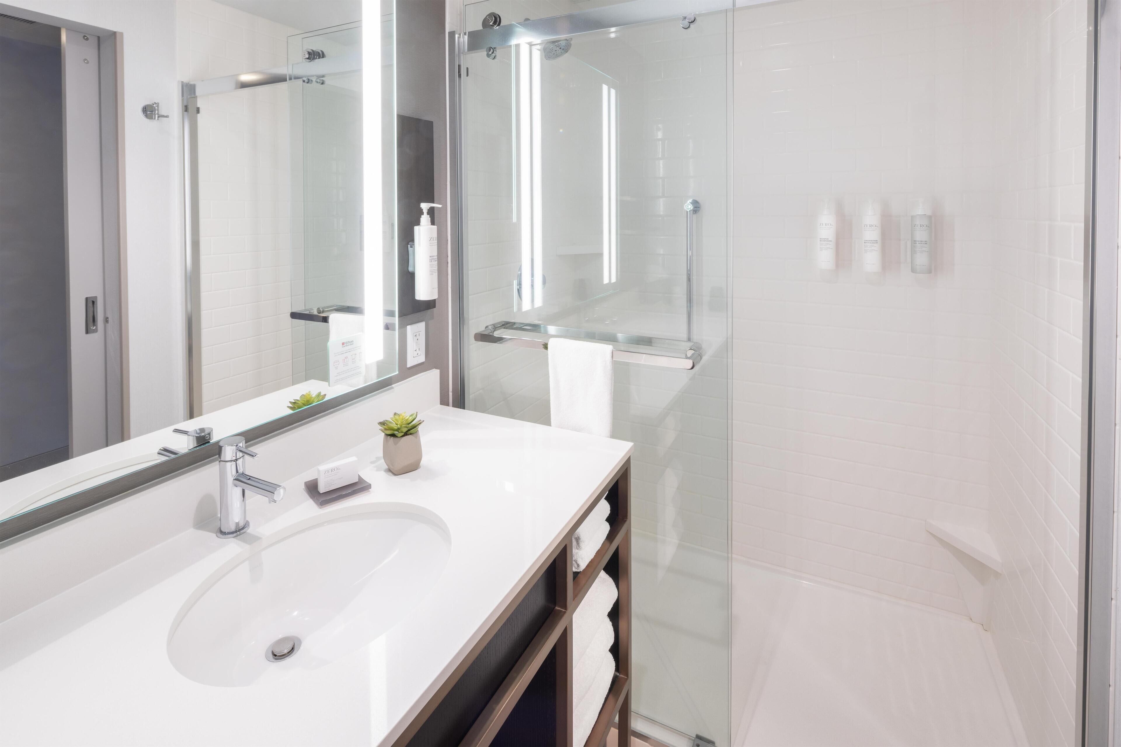 A modern bathroom with a glass shower enclosure, a large mirror, and a white sink.