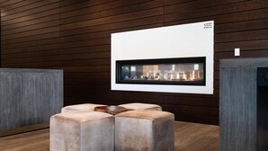 A modern interior with a fireplace, cushioned seating, and wooden panel walls. - Hilton Garden Inn Redmond Seattle (Redmond)
