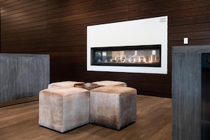 A modern interior with a fireplace, cushioned seating, and wooden panel walls. - Hilton Garden Inn Redmond Seattle (Redmond)