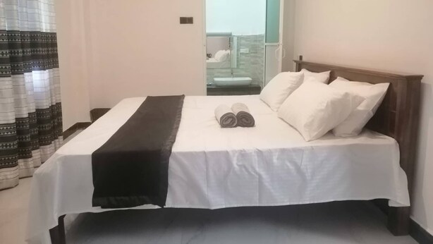 A hotel room with a bed, a bathroom visible through an open door, and a balcony with a glass railing. - Signature Kandy (Kandy)