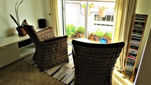 Parvekkeella on rottinkituoleja, pieni pöytä ja ruukussa oleva kasvi.