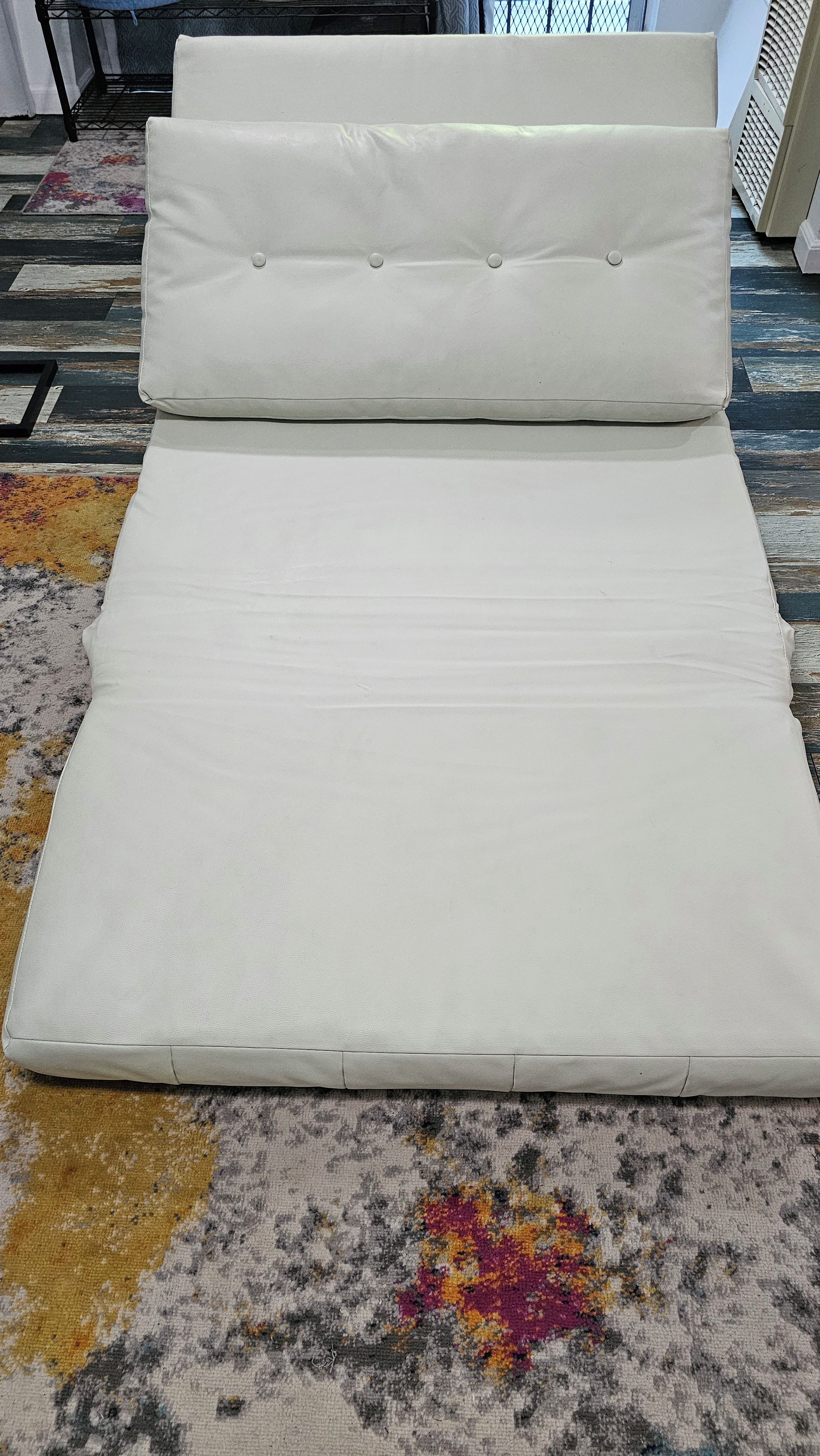 Ein Bett mit einer weißen Matratze und zwei Kissen auf einem gemusterten Teppich.