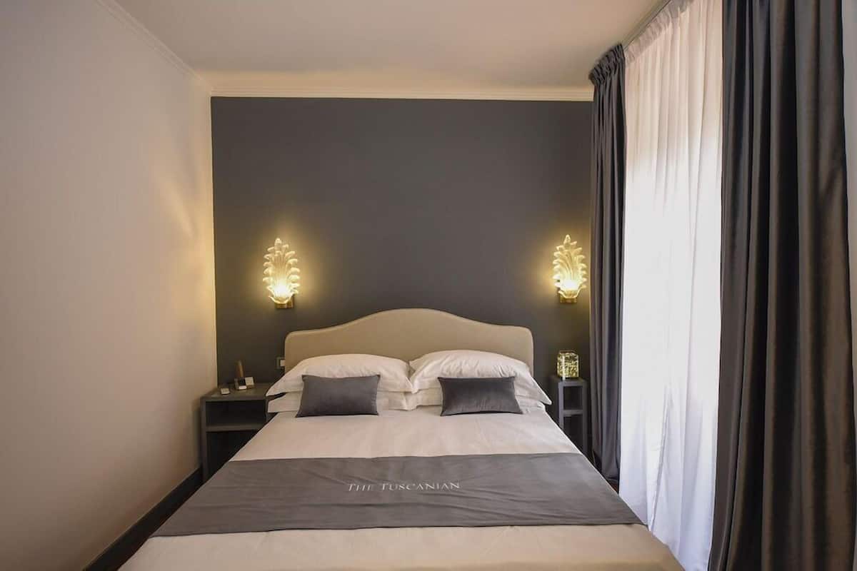 A hotel room with a bed, two bedside tables, and a nightstand.
