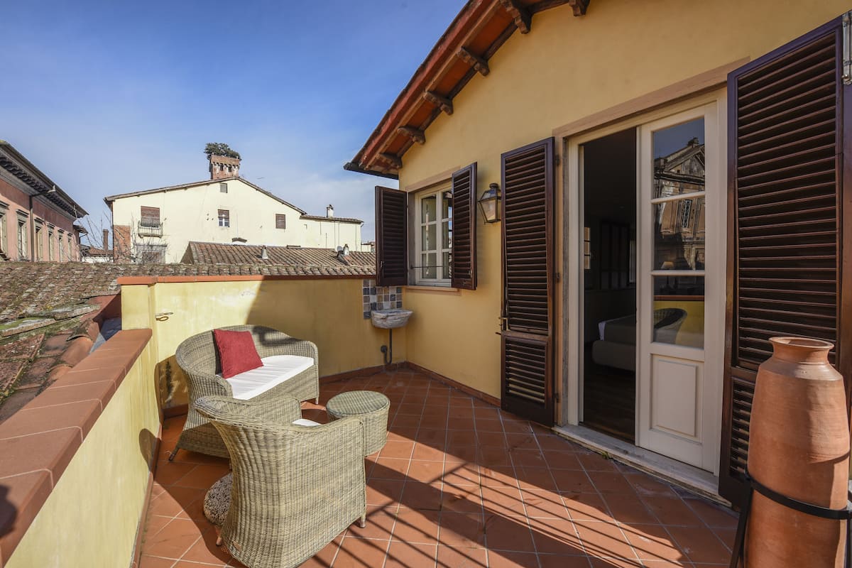 A patio with wicker furniture, a tiled floor, and a large clay pot.