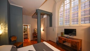 A hotel room with a bed, a desk, a television, and a large window with a view of the outside. - The Tuscanian Hotel (Lucca)
