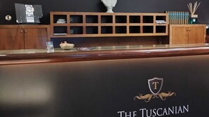 A reception desk at The Tuscanian Hotel with a plaque, a bust, and a wooden cabinet. - The Tuscanian Hotel (Lucca)