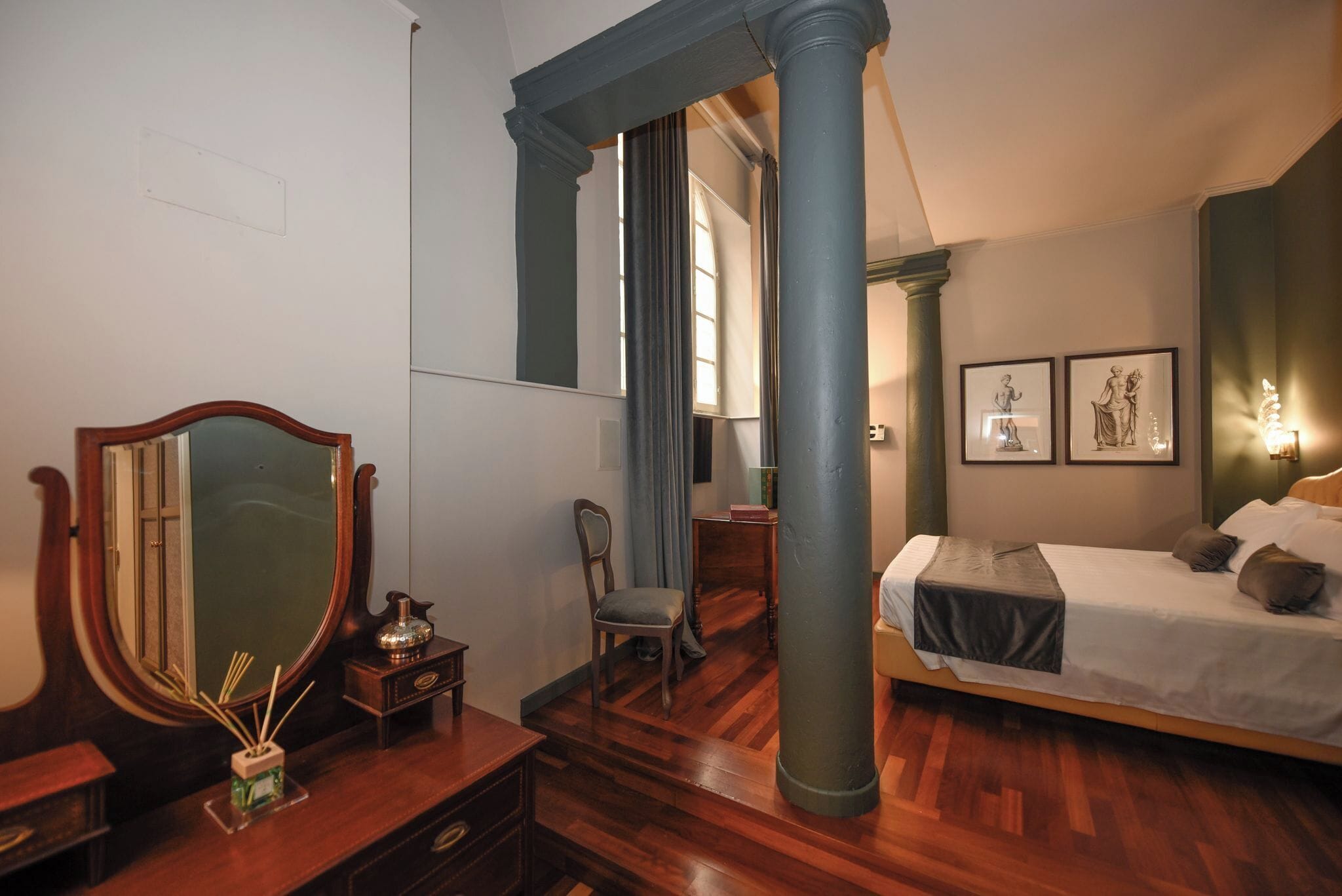 A bedroom with a wooden bed, a large mirror, a chair, and a desk.