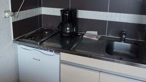 A compact kitchenette with a microwave, coffee maker, and a sink.