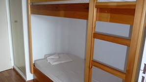 A bunk bed in a room with wooden flooring and white walls.