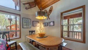 A dining area with a wooden table, benches, and a hanging light fixture. - The Lodge: Comfort&Hospitality AC/4bdrm/10 beds/beach (Soda Springs)
