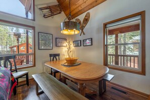 A dining area with a wooden table, benches, and a hanging light fixture.