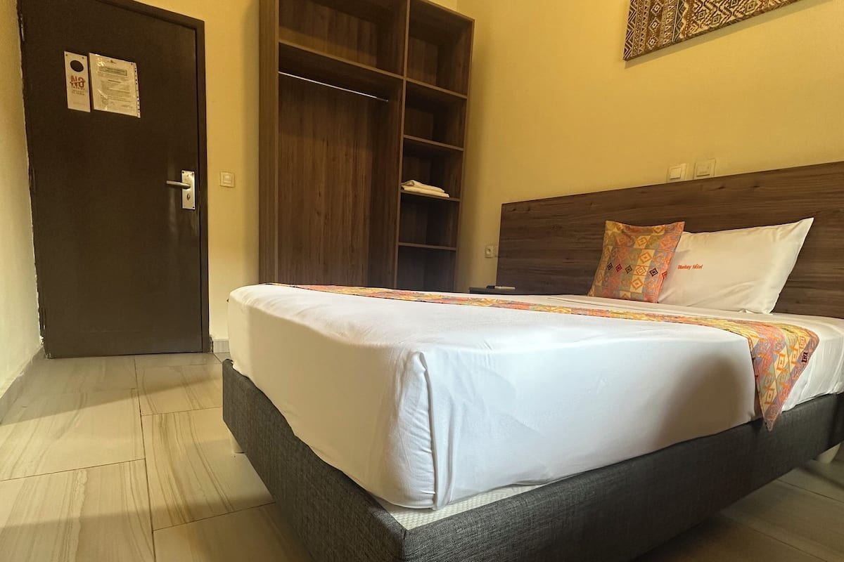 Ein Hotelzimmer mit Bett, Kleiderschrank und Tür.