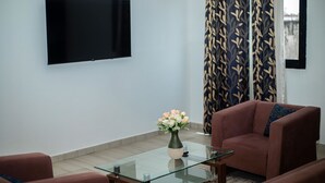 Un soggiorno moderno con un tavolino in vetro, un divano marrone e una TV a parete.