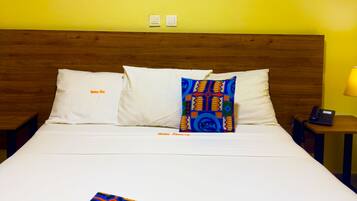 Habitación de hotel con cama, dos mesitas de noche, una lámpara y un cuadro en la pared.