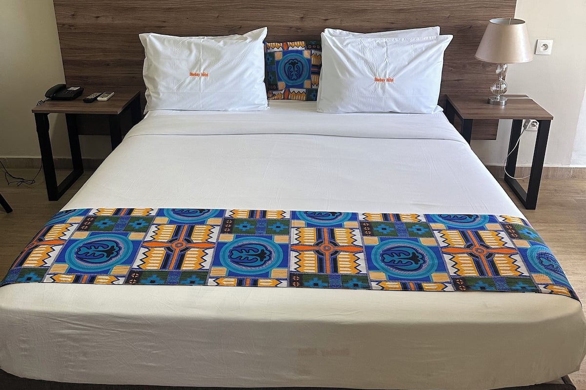 Ein Hotelzimmer mit einem großen Bett, zwei Nachttischen, einer Wandlampe und einem dekorativen Wandbild.