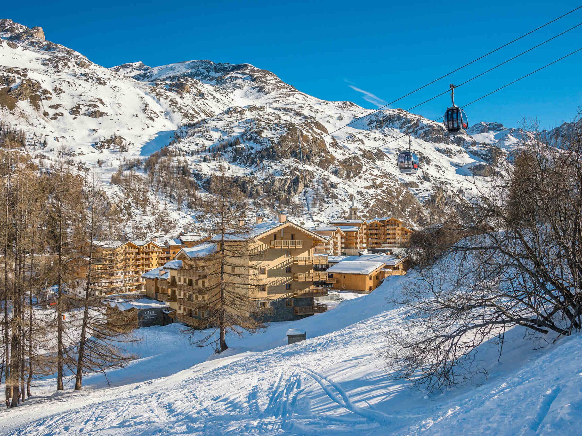 A snow-covered mountain with a ski lift and a lodge with multiple floors and balconies.