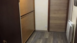 Un pasillo estrecho con piso de madera y una puerta que da a una habitación.