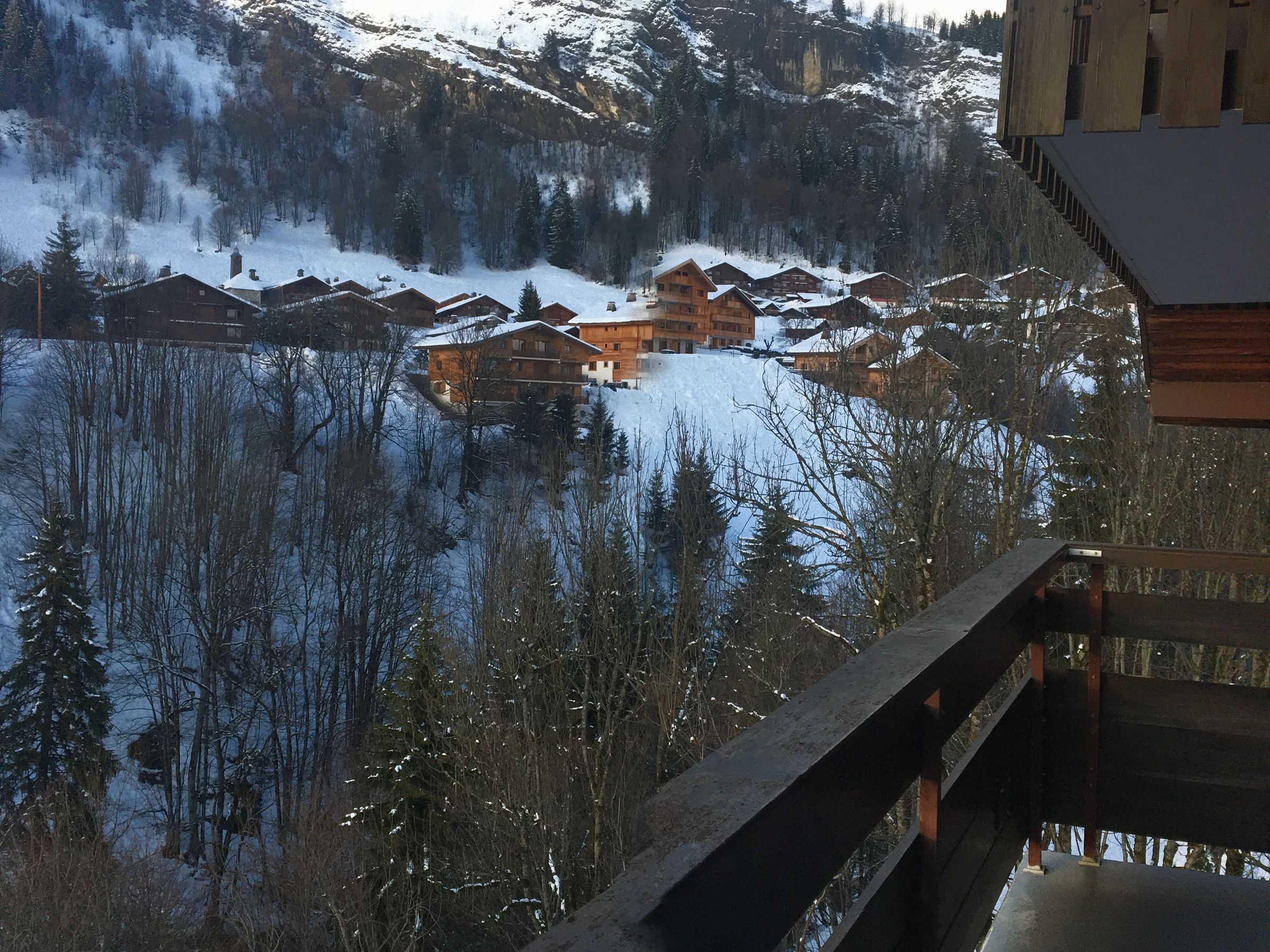 A mountain lodge with multiple wooden cabins, surrounded by snow-covered trees and a lake.
