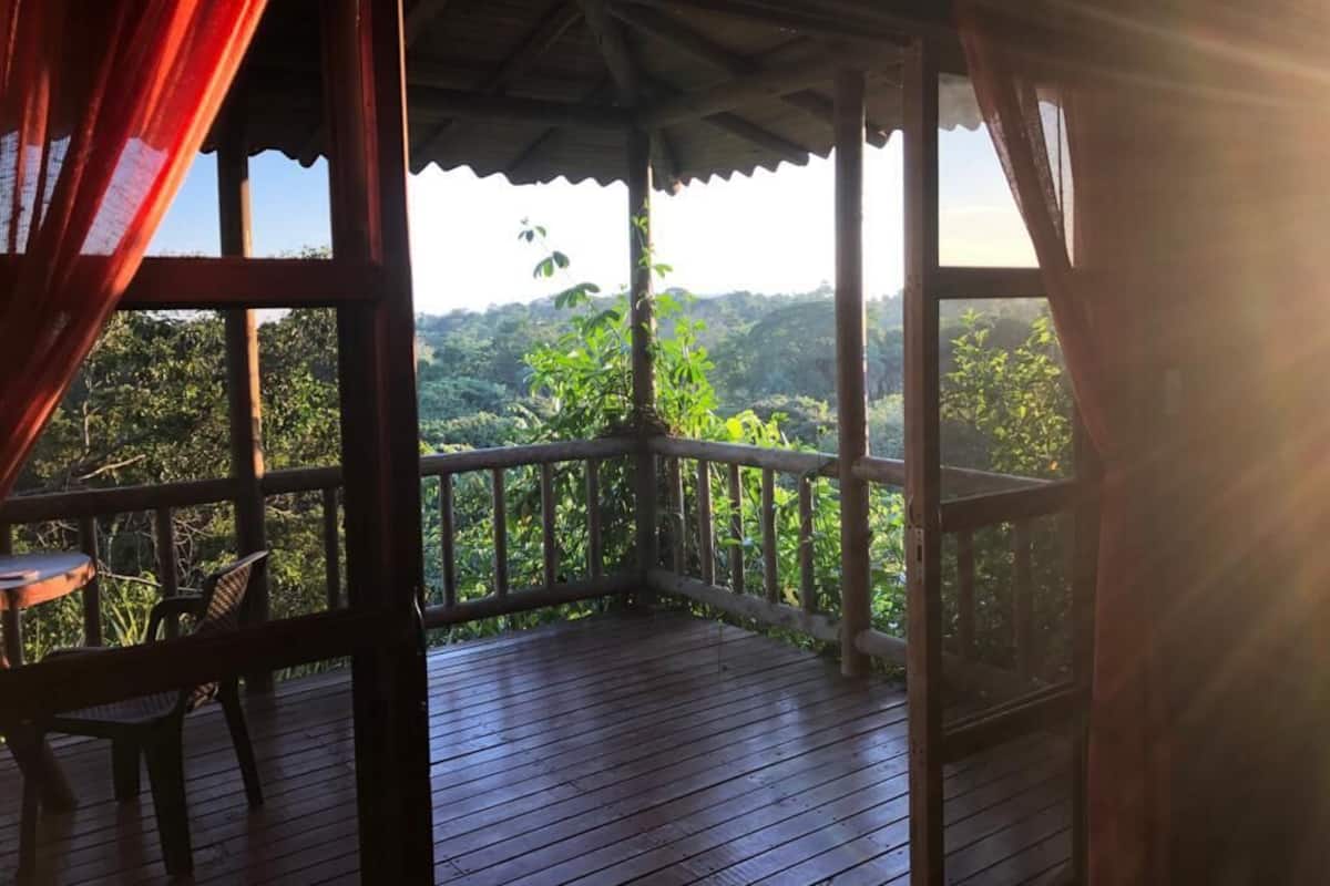 A wooden deck with a table and chairs, overlooking a lush green landscape.