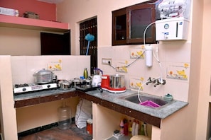 A compact kitchen with a gas stove, a sink, a water purifier, and a small window.