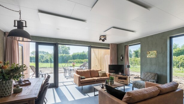 Un salon spacieux doté d’un grand téléviseur, de sièges confortables et offrant une vue sur l’extérieur.