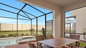 A covered patio with a pool, outdoor furniture, and a view of the surrounding area. - Westside Charm | Games Room | Kids Bedrooms (Kissimmee)