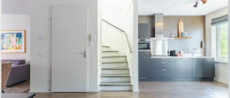 Een moderne keuken met grijze kastjes, een ingebouwde oven en een raam met uitzicht op groen.