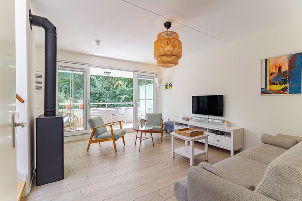 A modern living room with a fireplace, a television, and a balcony with outdoor furniture.