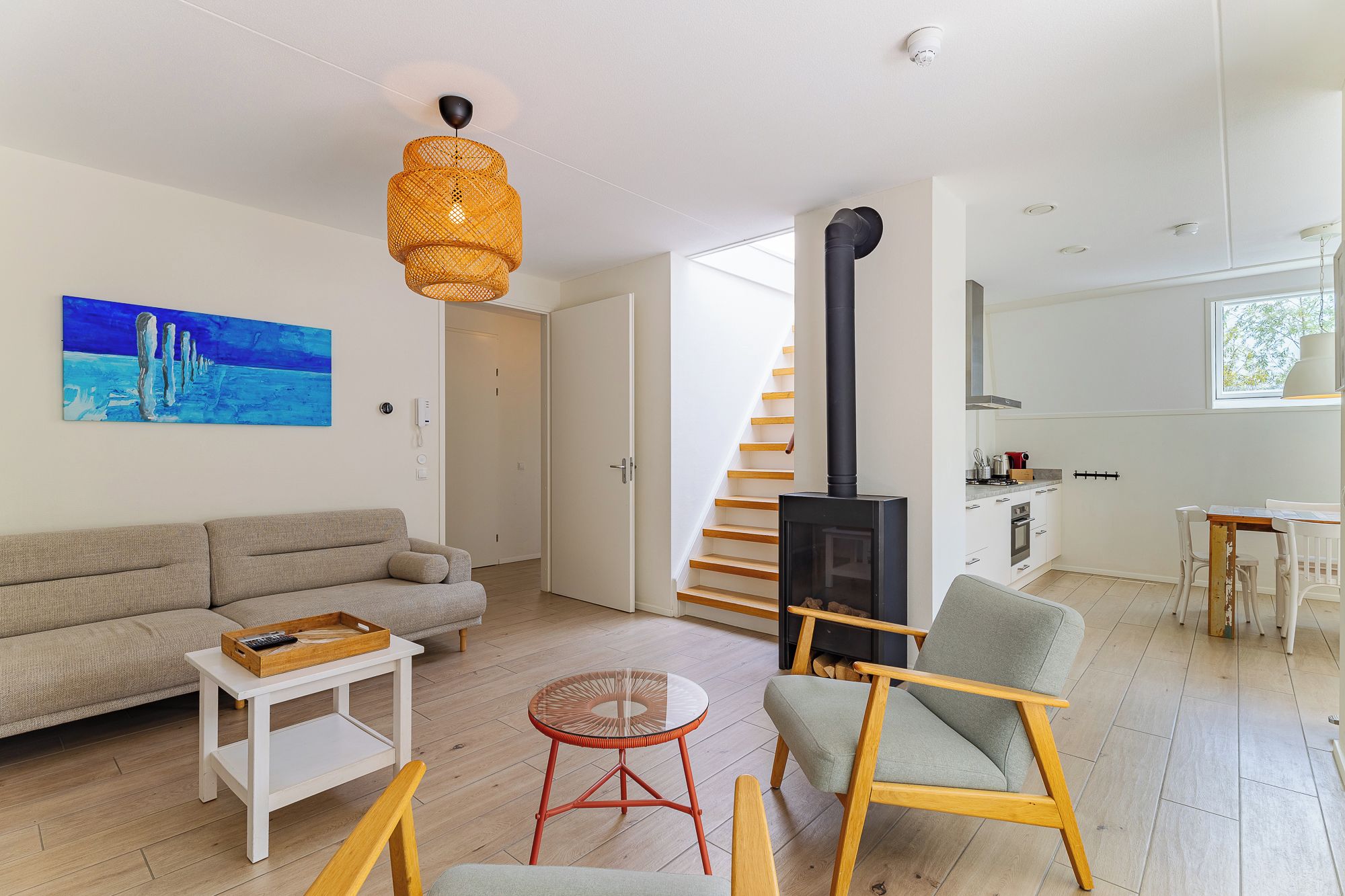 A modern living room with a sofa, a coffee table, a red chair, a glass table, and a fireplace.