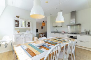 Eine moderne Küche mit weißen Schränken, einer zentralen Kochinsel mit bunten Tischdecken und Pendelleuchten.