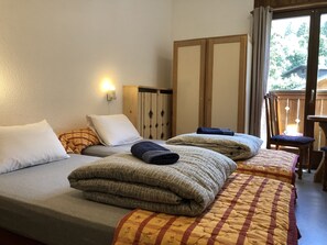 Habitación de hotel con dos camas, un armario de madera, una silla y vistas al exterior.