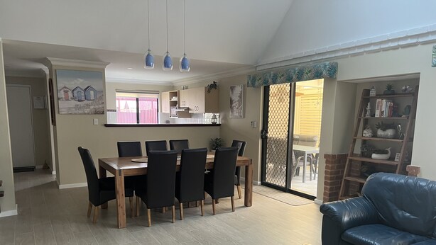A spacious living room with a dining area, a blue leather sofa, and a wooden coffee table.