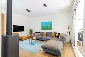 A modern living room with a sofa, a flat-screen TV, a painting, and a fireplace.