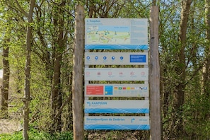 A directional signpost with multiple panels, including a map and various symbols indicating facilities and regulations.