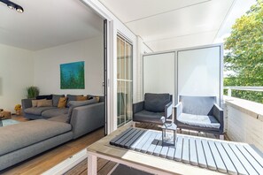 A modern living room with a grey sofa, a coffee table, and a large window. - Apt - Kaapduinseweg 13 | Dishoek "13N Lu (Koudekerke)