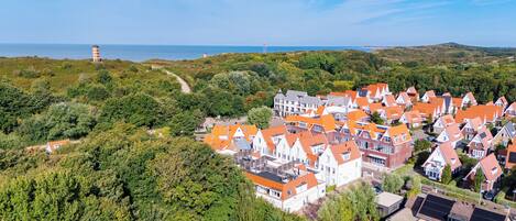 A coastal town with traditional red-roofed houses, a lighthouse, and a mix of residential and commercial buildings.
