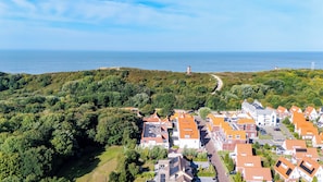 A coastal village with terraced houses, a lighthouse, and a clear view of the sea.