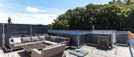An outdoor patio area with a sectional sofa and a small table.