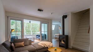 A modern living room with a sofa, two small tables, a fireplace, and a staircase.