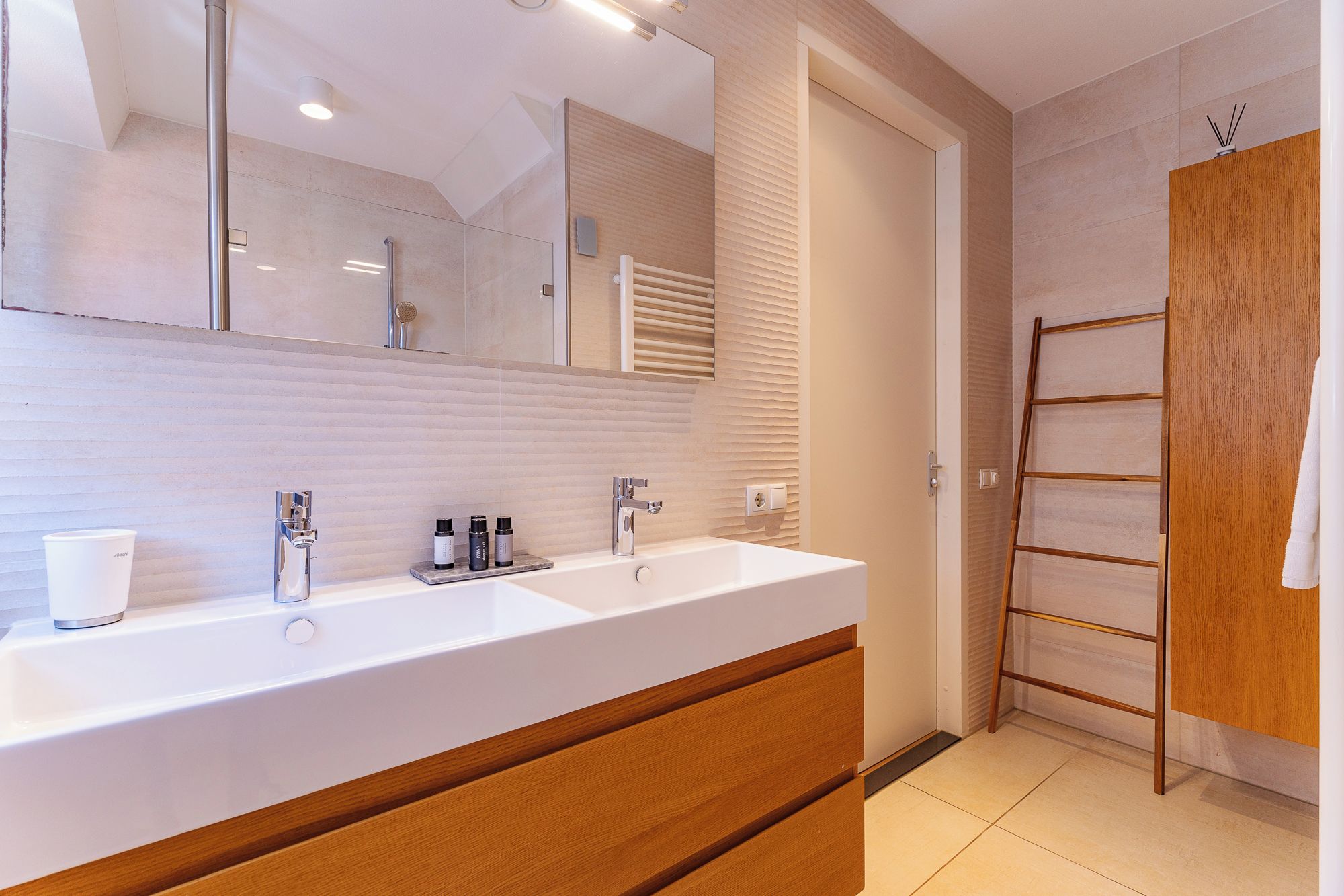 Une salle de bain moderne avec un double lavabo, un miroir et un meuble-lavabo en bois.