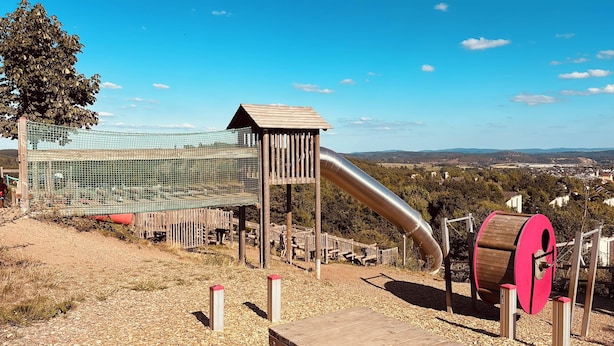 Un parque infantil con tobogán, red de escalada y una torre de vigilancia.