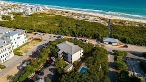 Vista aérea de una zona costera con playa, muelle y aparcamiento junto a varios edificios.