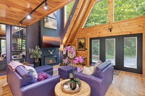 A modern interior with a fireplace, seating area, and large windows.
