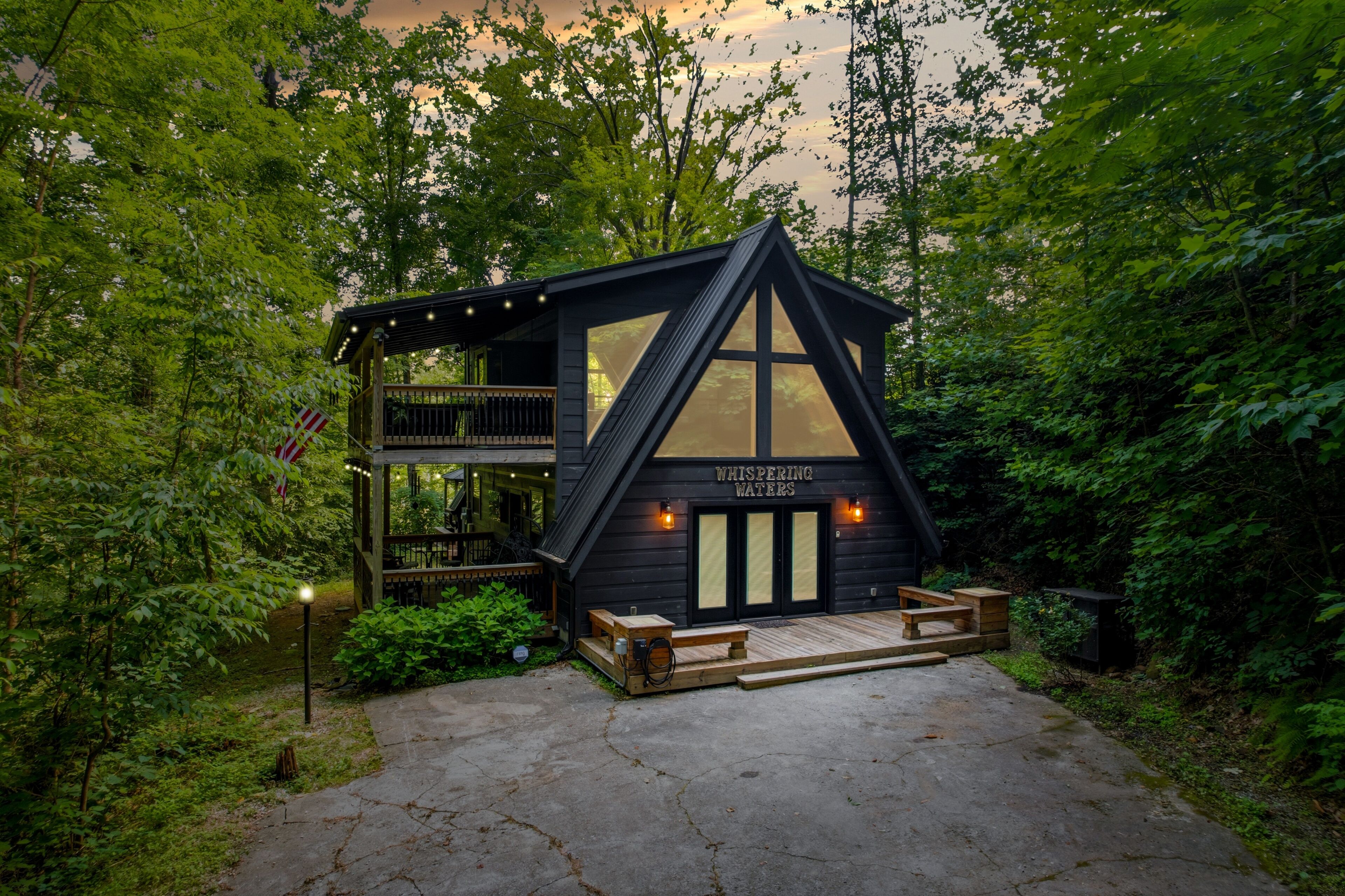 A cabin with a two-story structure, a deck, and a sign reading 'WHISPERING WATERS'.