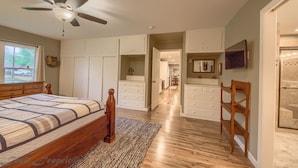 A bedroom with a bed, a ceiling fan, and a walk-in closet.