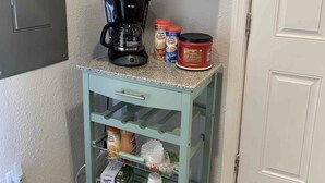 Zona de cuina amb espai de cafè, incloent cafetera, tasses i recipients de cafè.