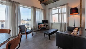 Ein modernes Wohnzimmer mit einer Couch, Sesseln, einem Tisch und einem Fernseher.