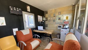 A room with orange and white furniture, a desk with a laptop, a small refrigerator, and a window with a view. - Kapadokya Deluxe Apart (Ürgüp)